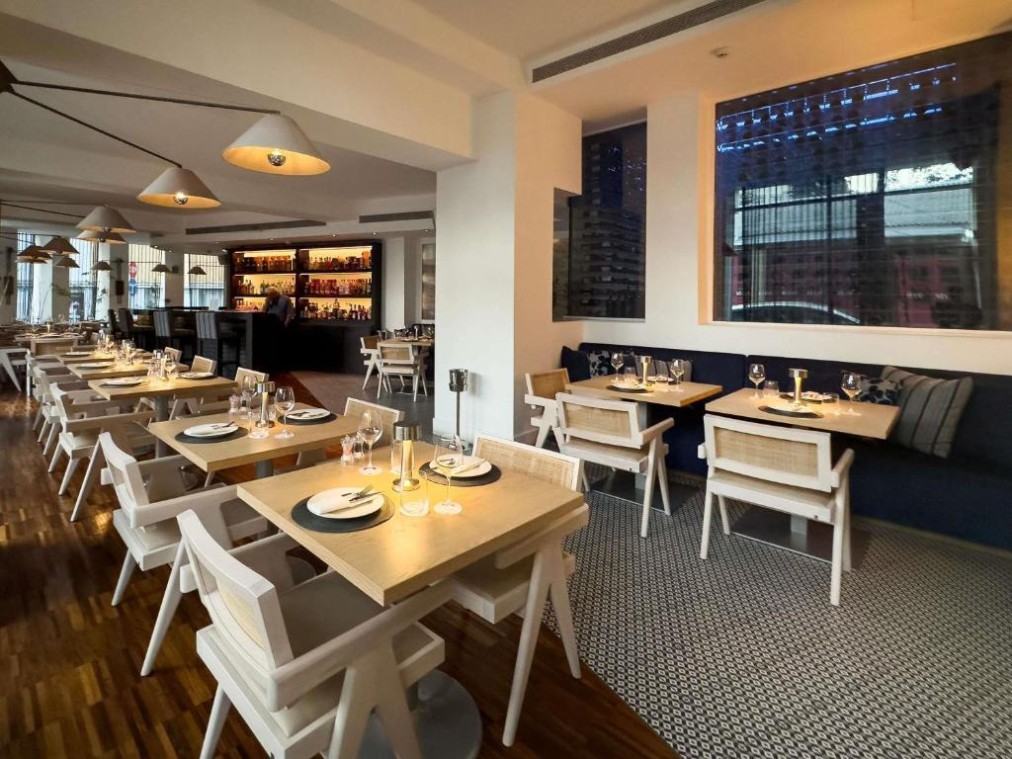 Dining room with laid tables, lounge seating and a bar at the far end.