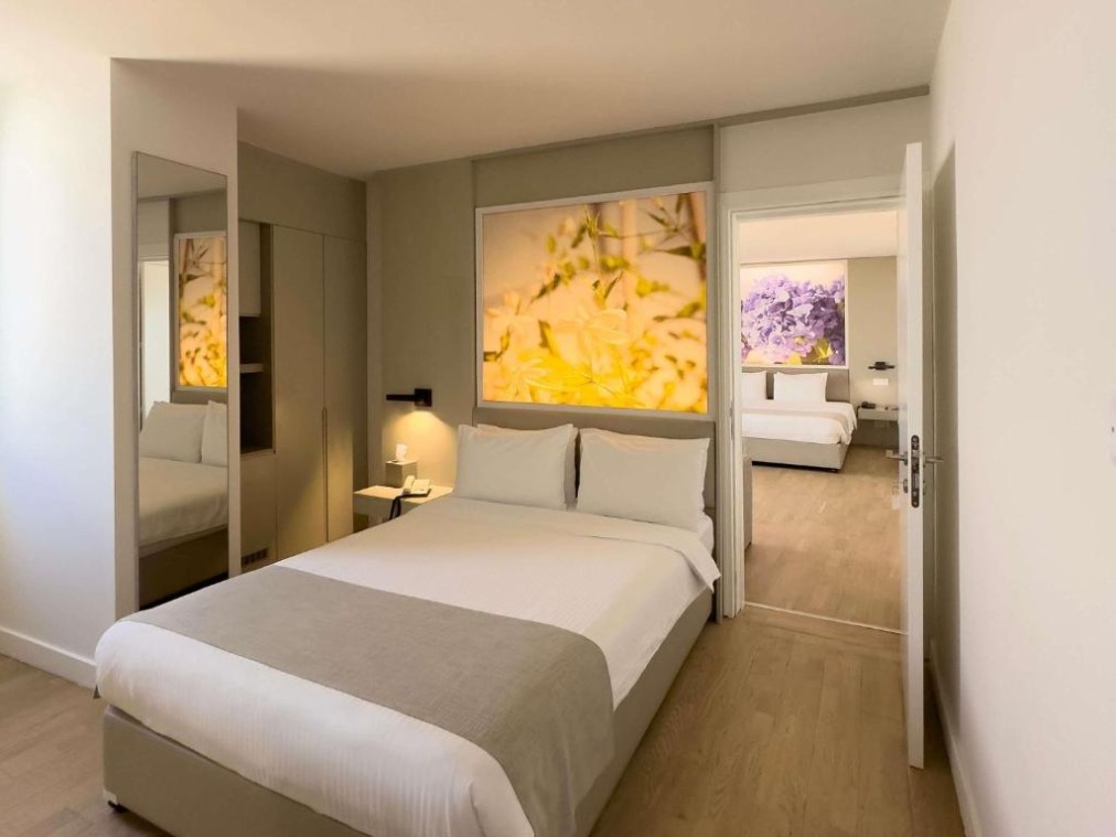 Bedroom with double bed and wardrobe, connected to a second room in the background.