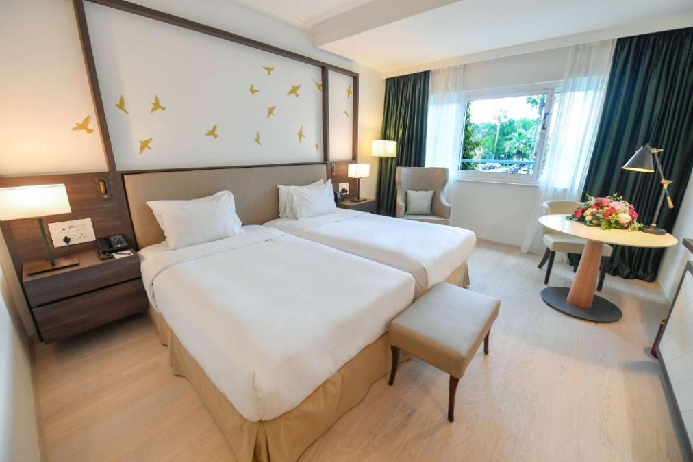 Twin guest room with round table, flowers and window seating.