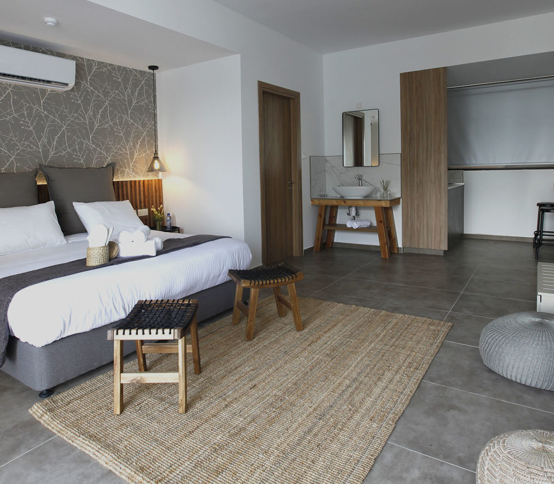 Stylish studio room with bed, stools, rug, and modern wooden furnishings