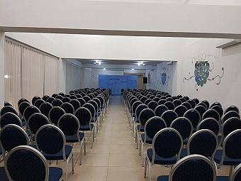 Conference room with rows of blue cushioned chairs facing a presentation area