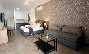 Spacious suite with double bed, sofa, and modern decor featuring gray tones and patterned wall