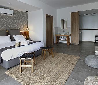 Stylish studio room with bed, stools, rug, and modern wooden furnishings