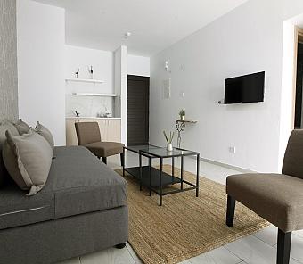 Lounge area with gray sofa, chairs, and TV, decorated in a simple, contemporary style