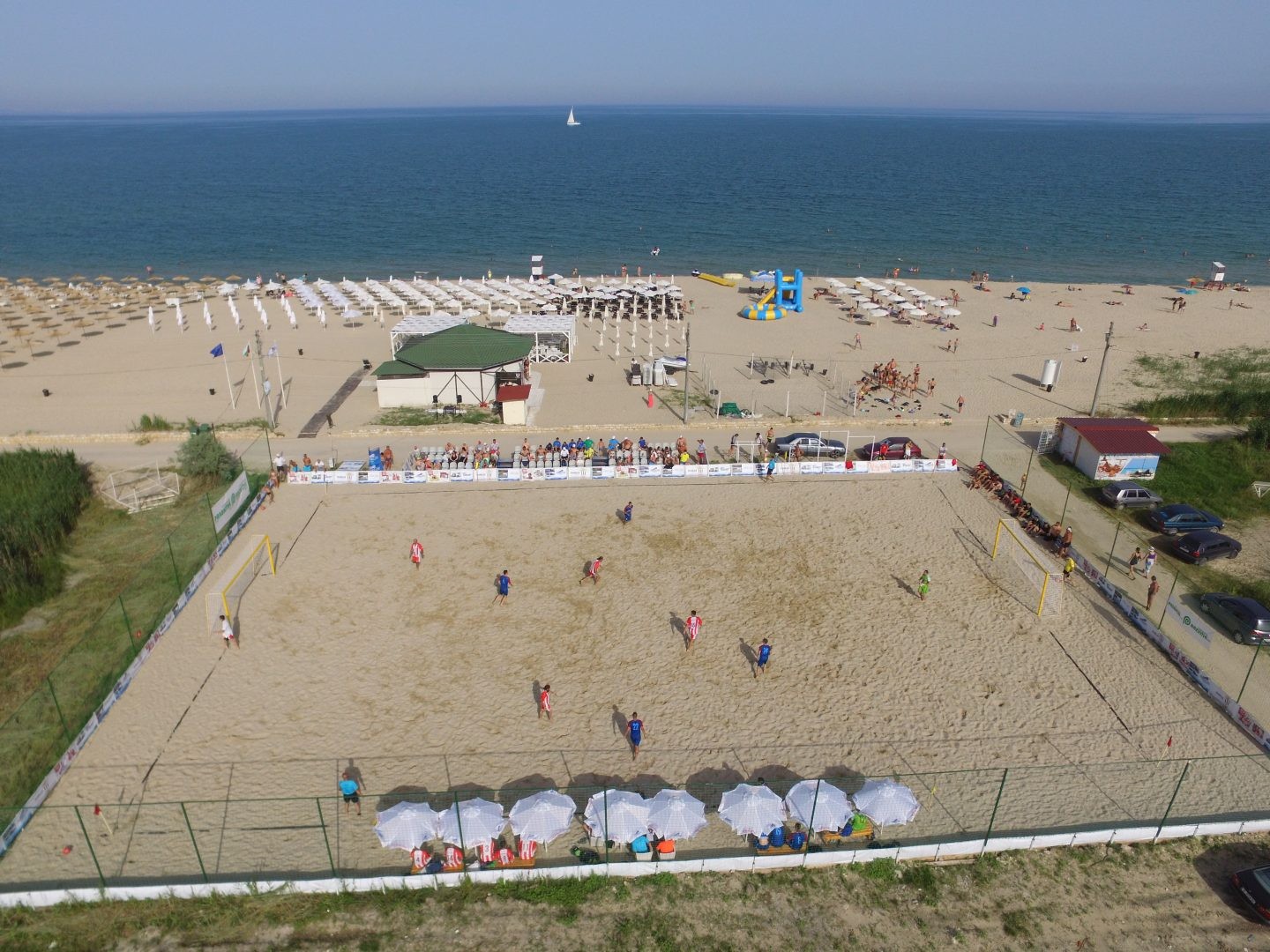 Vue aérienne de terrains de beach-volley au bord de la mer, accueillant les exercices et matchs du stage d'entraînement