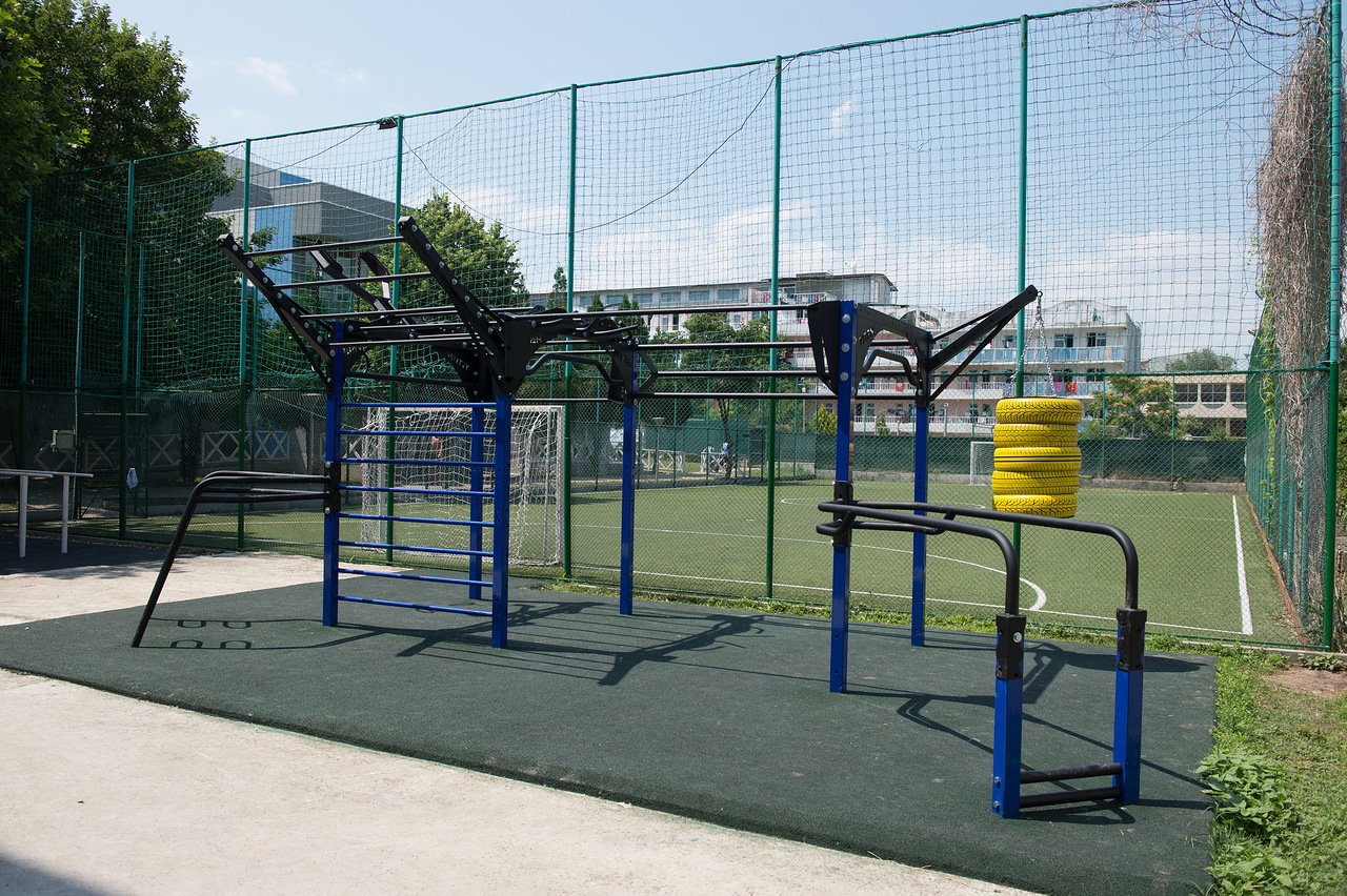 Zone de fitness extérieure avec barres de traction et obstacles, conçue pour les exercices de force pendant le stage d'entraînement