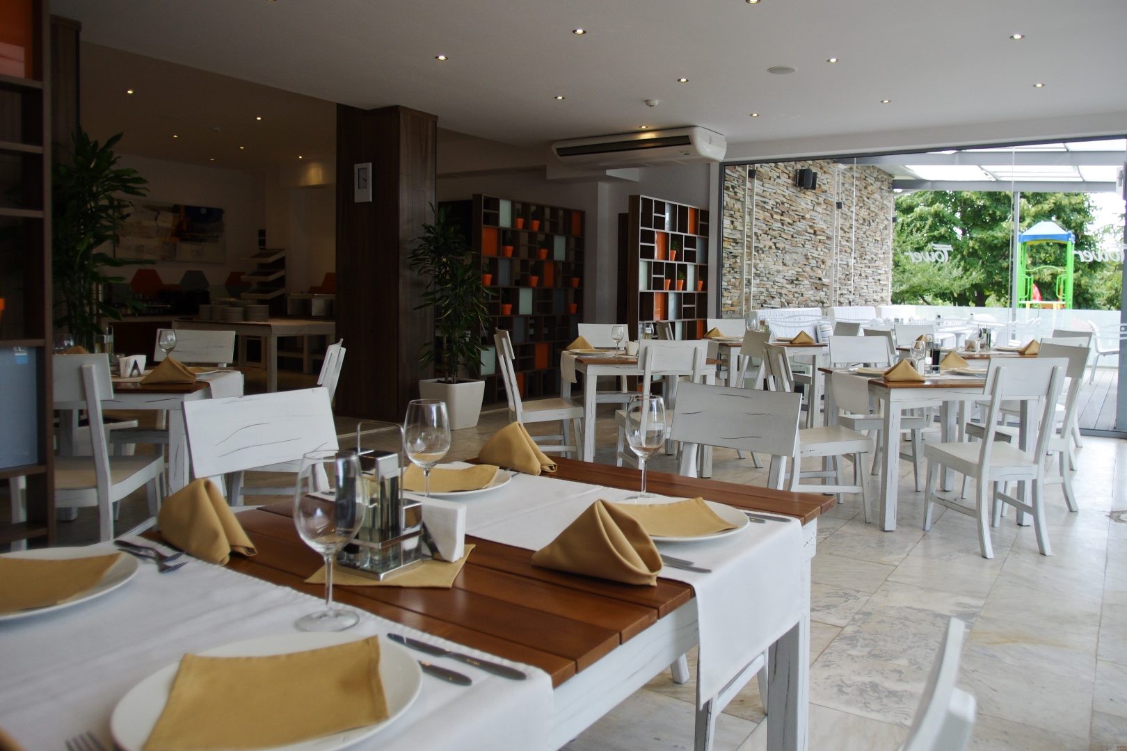 Restaurant lumineux avec tables blanches, surfaces en bois et couverts pour les repas d'équipe au stage d'entraînement