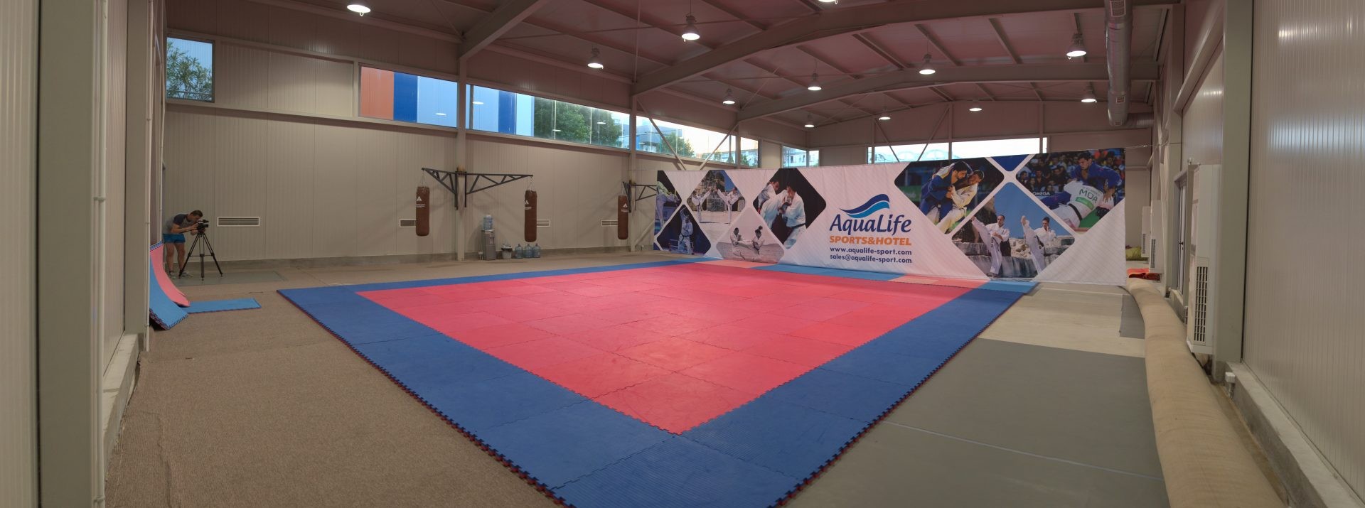 Grande zone de tapis intérieure avec bannières et équipement, aménagée pour les exercices structurés du stage d'entraînement