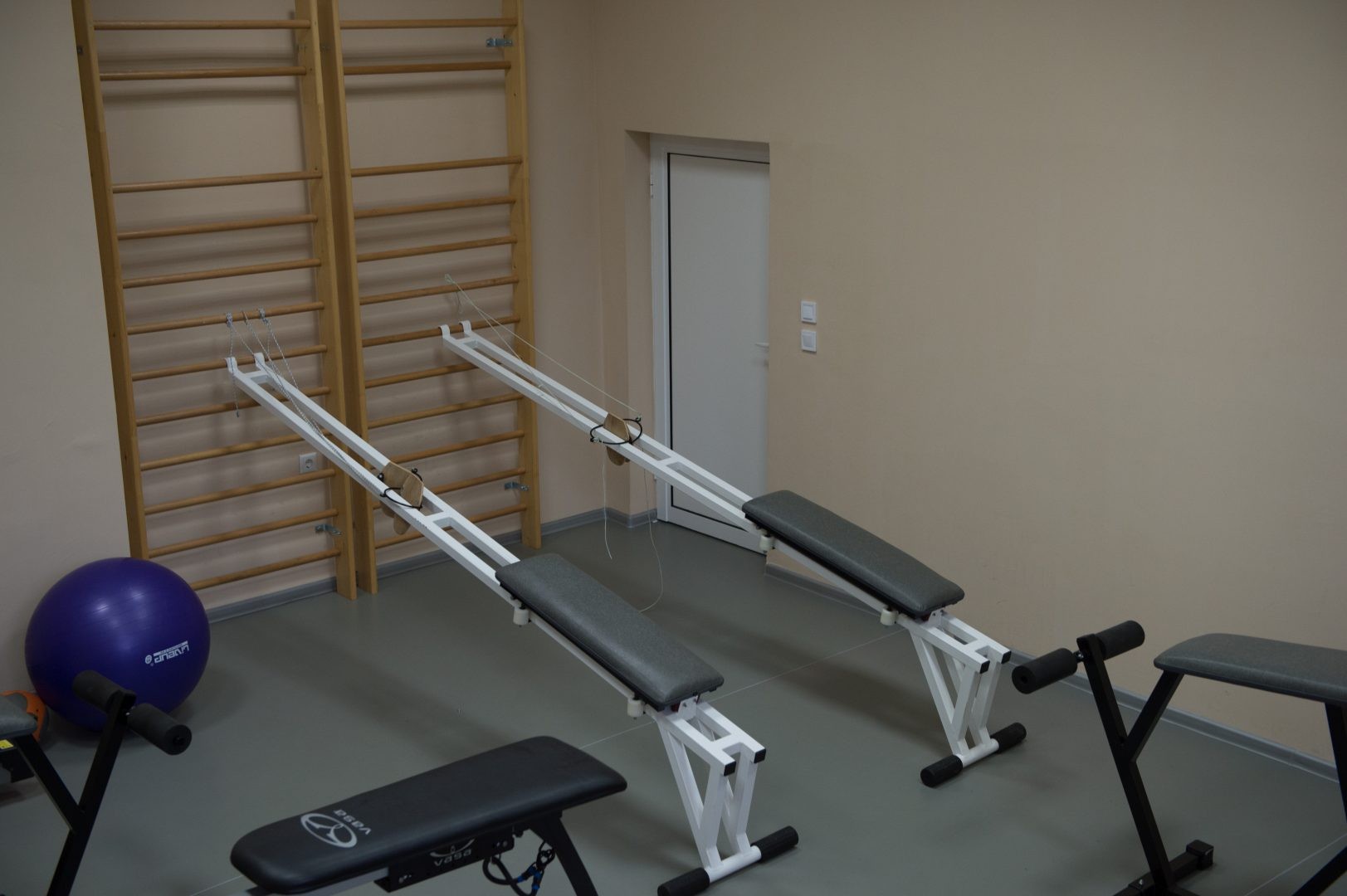 Petite salle d'entraînement avec bancs, espaliers et ballons d'exercice pour les exercices de rééducation ou de conditionnement