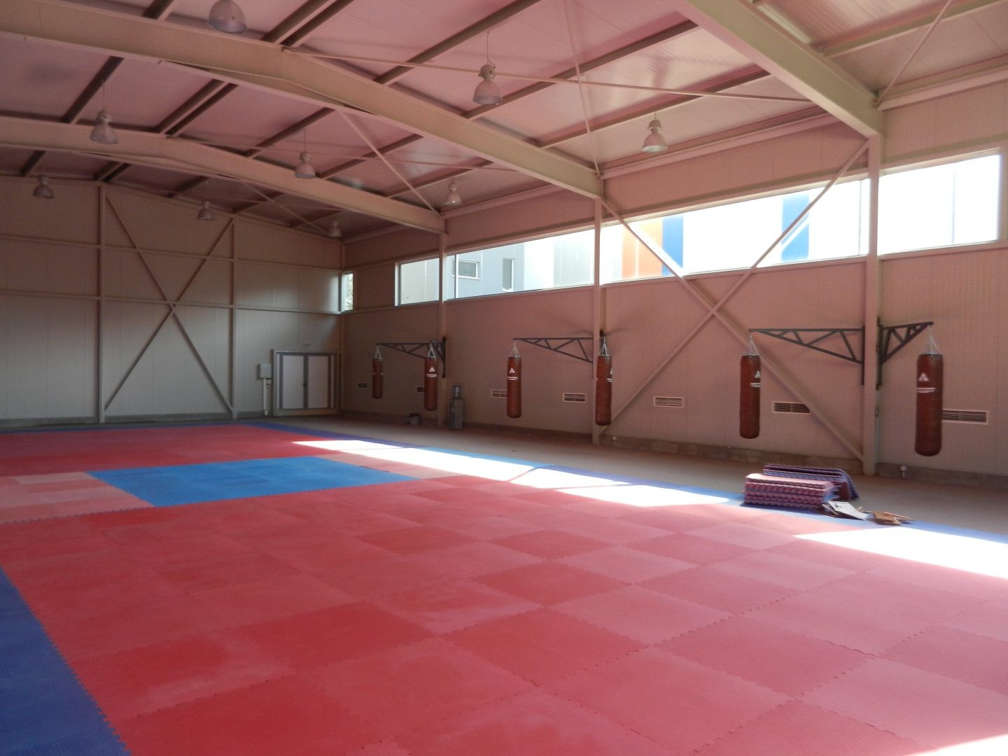 Salle de gym intérieure avec tapis de sol rouge et protections murales, prête pour les séances d'entraînement