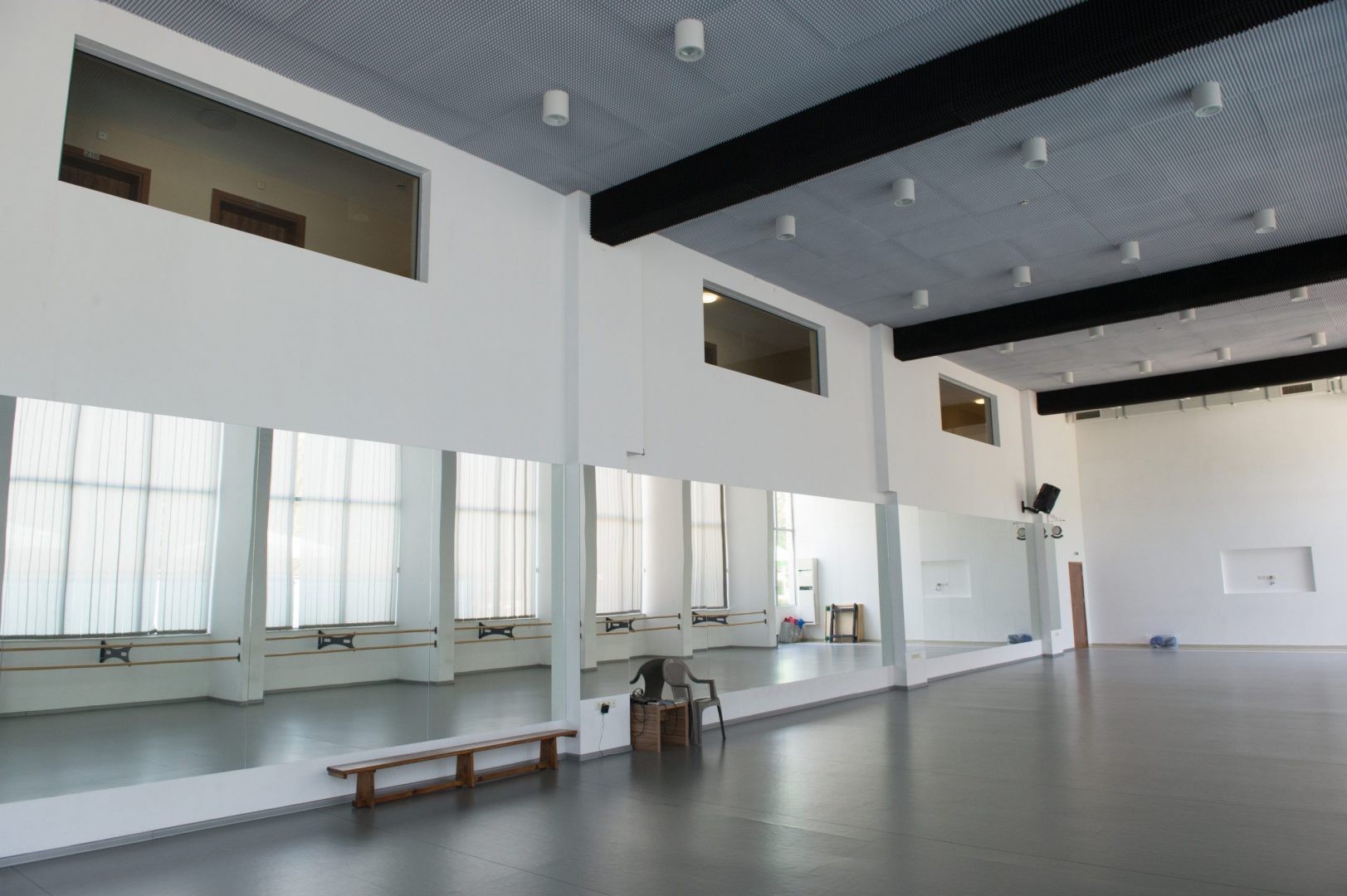 Studio spacieux avec miroirs, bancs et lumière naturelle, utilisé pour les séances de coaching et d'entraînement