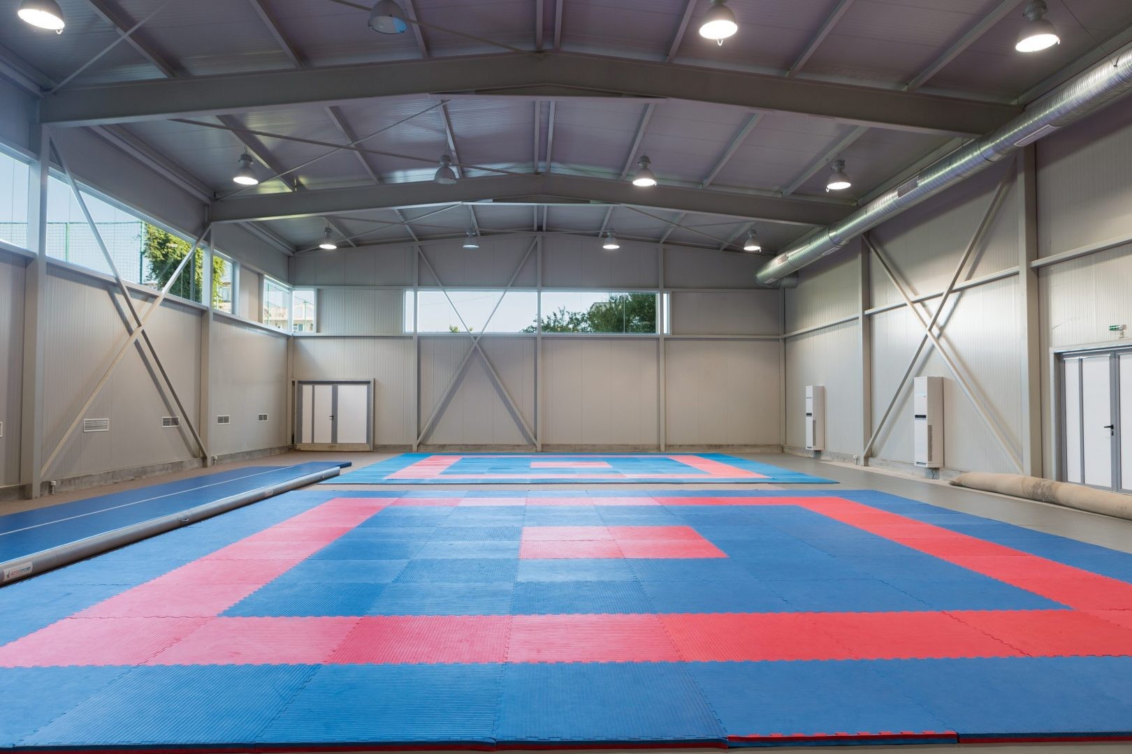 Salle d'entraînement intérieure avec tapis rouges et bleus, préparée pour le stage d'arts martiaux ou de gymnastique