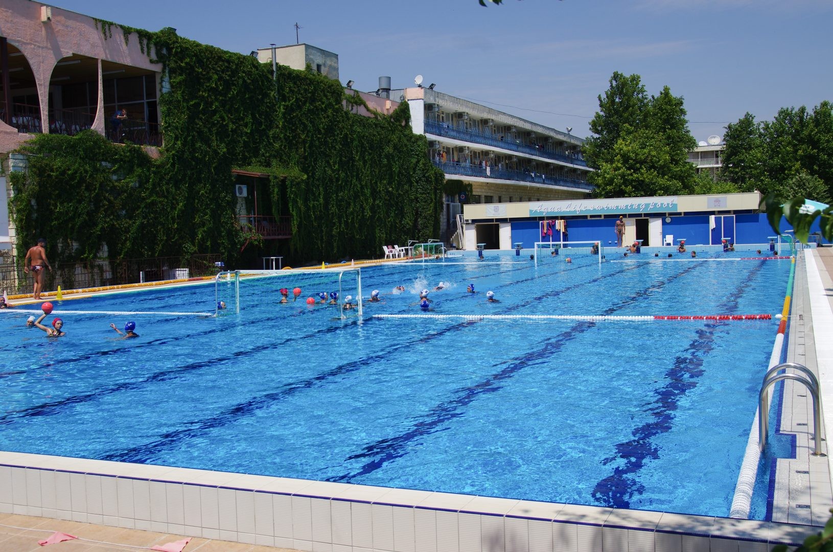 Nageurs s'entraînant dans une piscine extérieure avec lignes d'eau, dans le cadre d'un stage d'entraînement