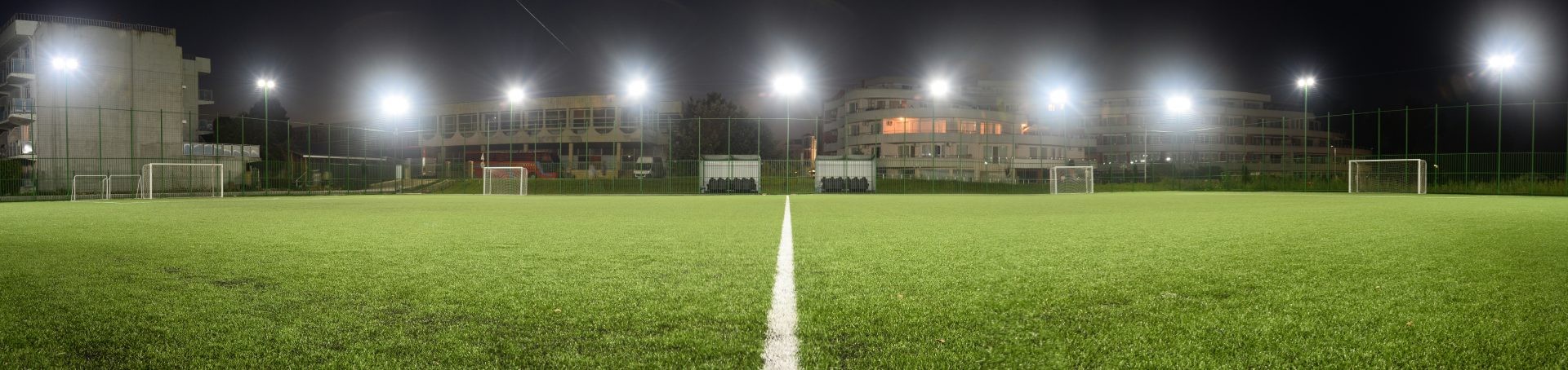 Vue nocturne d'un terrain de football illuminé avec ligne médiane et buts, préparé pour les séances d'entraînement en soirée