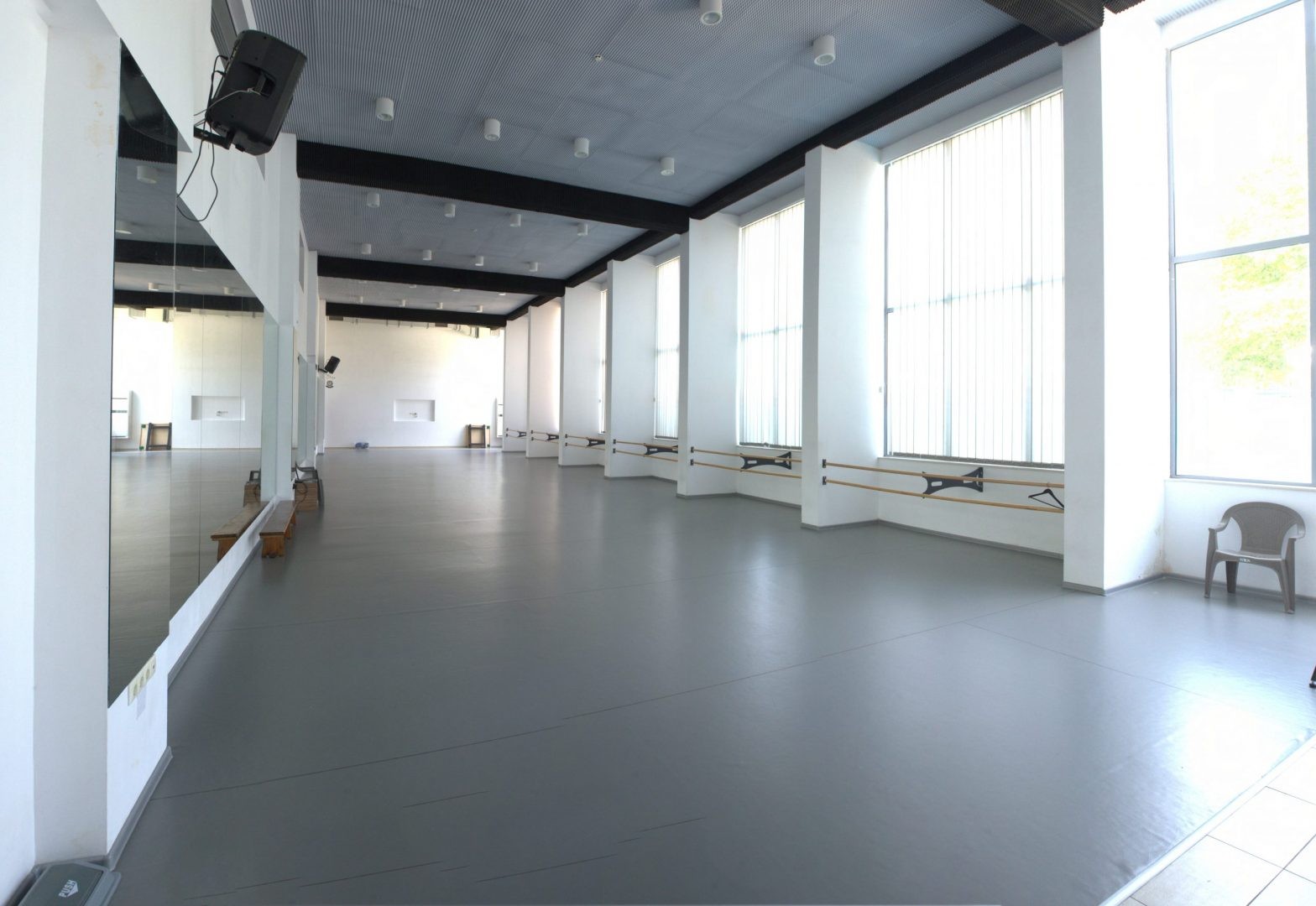 Studio de danse ou de fitness intérieur vide avec sol gris, miroirs et grandes fenêtres pour les entraînements du stage