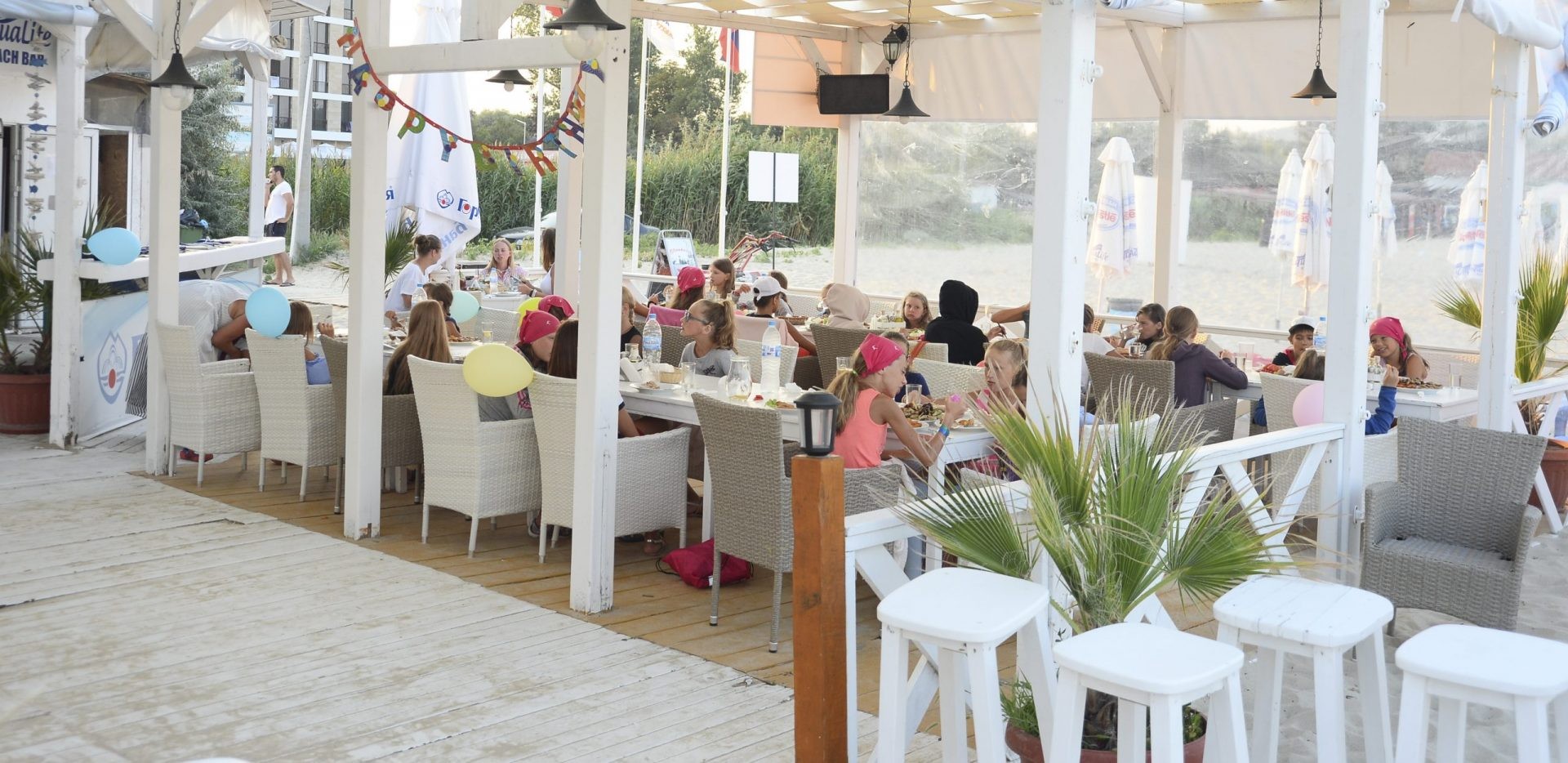Terrasse extérieure couverte avec mobilier blanc et clients, servant les repas de groupe pendant le stage d'entraînement