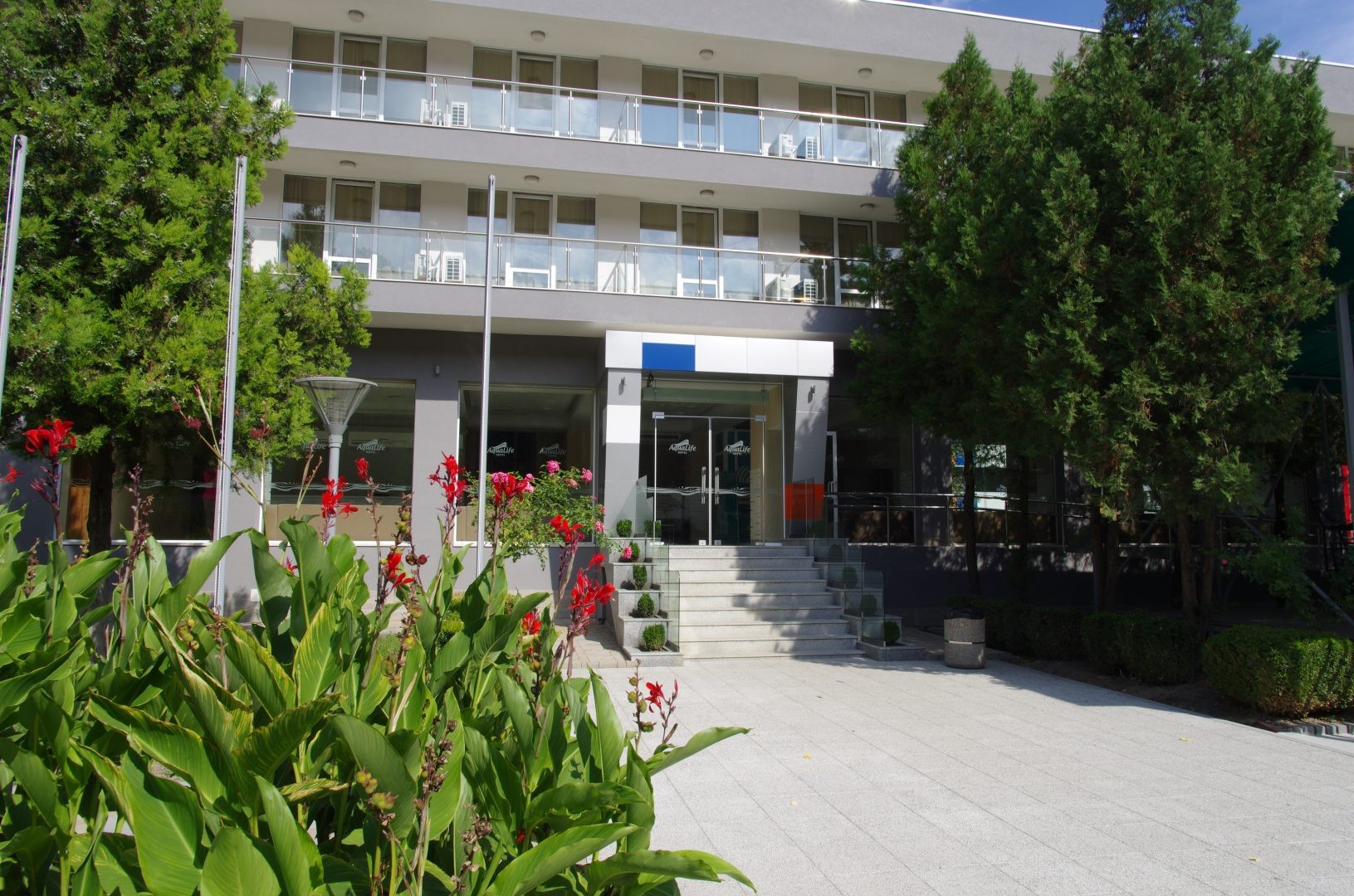 Entrée d'hôtel avec allée paysagée et balcons, hébergement pour les équipes en stage d'entraînement