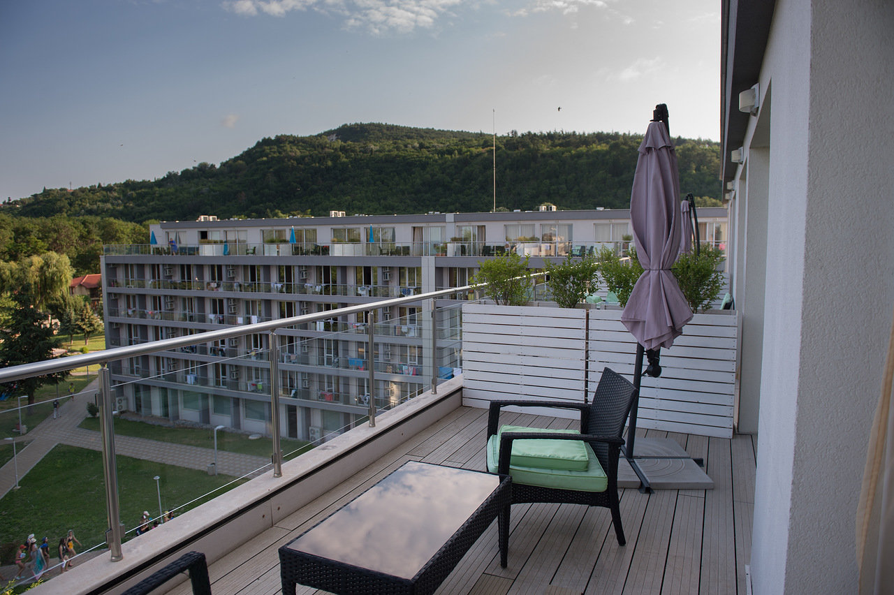 Balcon d'hôtel avec chaises et table extérieures donnant sur les bâtiments et la verdure, logement d'athlète pendant le stage d'entraînement