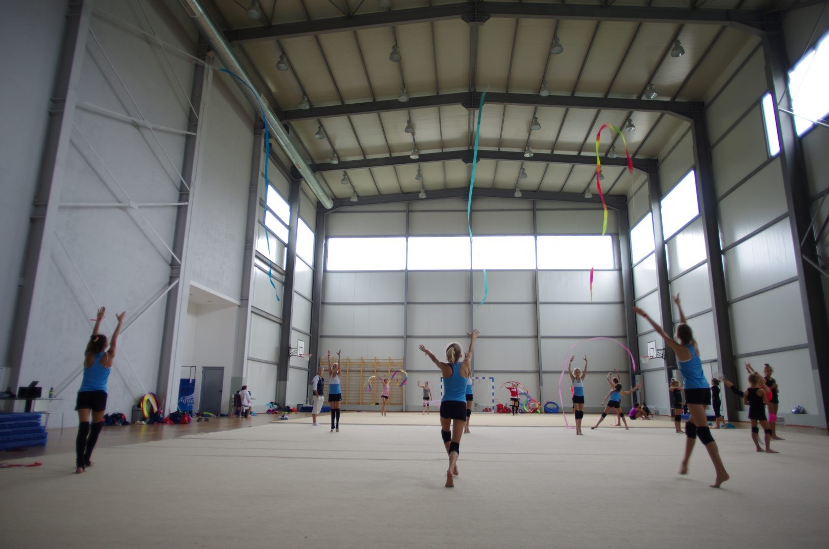 Athlètes pratiquant la gymnastique rythmique avec rubans dans une grande salle intérieure pendant une séance de stage d'entraînement