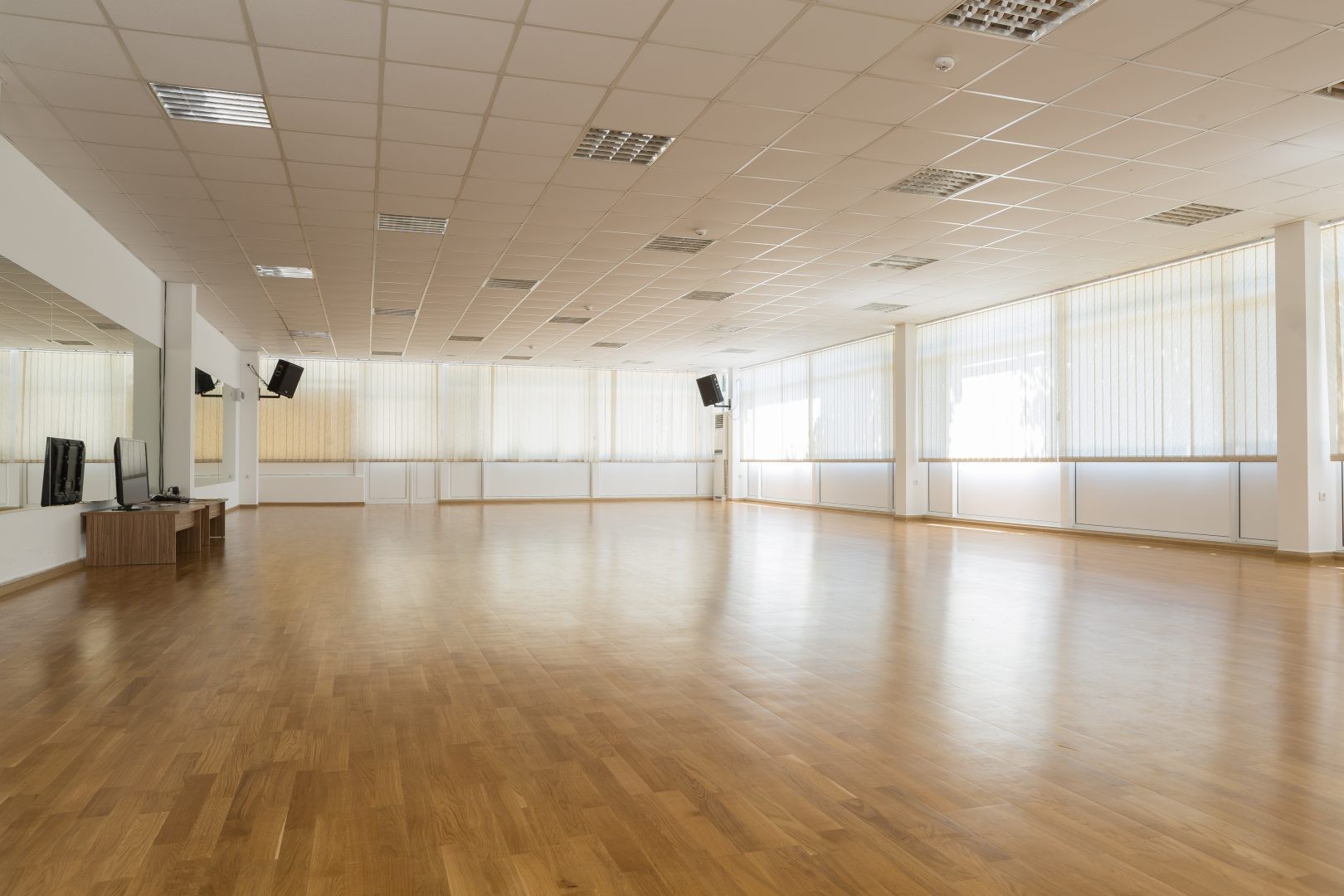 Studio intérieur lumineux avec parquet et miroirs, utilisé pour les entraînements fitness et les séances de coaching