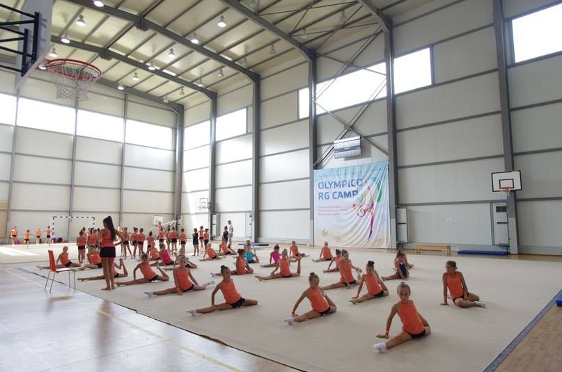 Groupe d'athlètes assis sur des tapis dans une salle de sport, écoutant les instructions pendant le stage d'entraînement