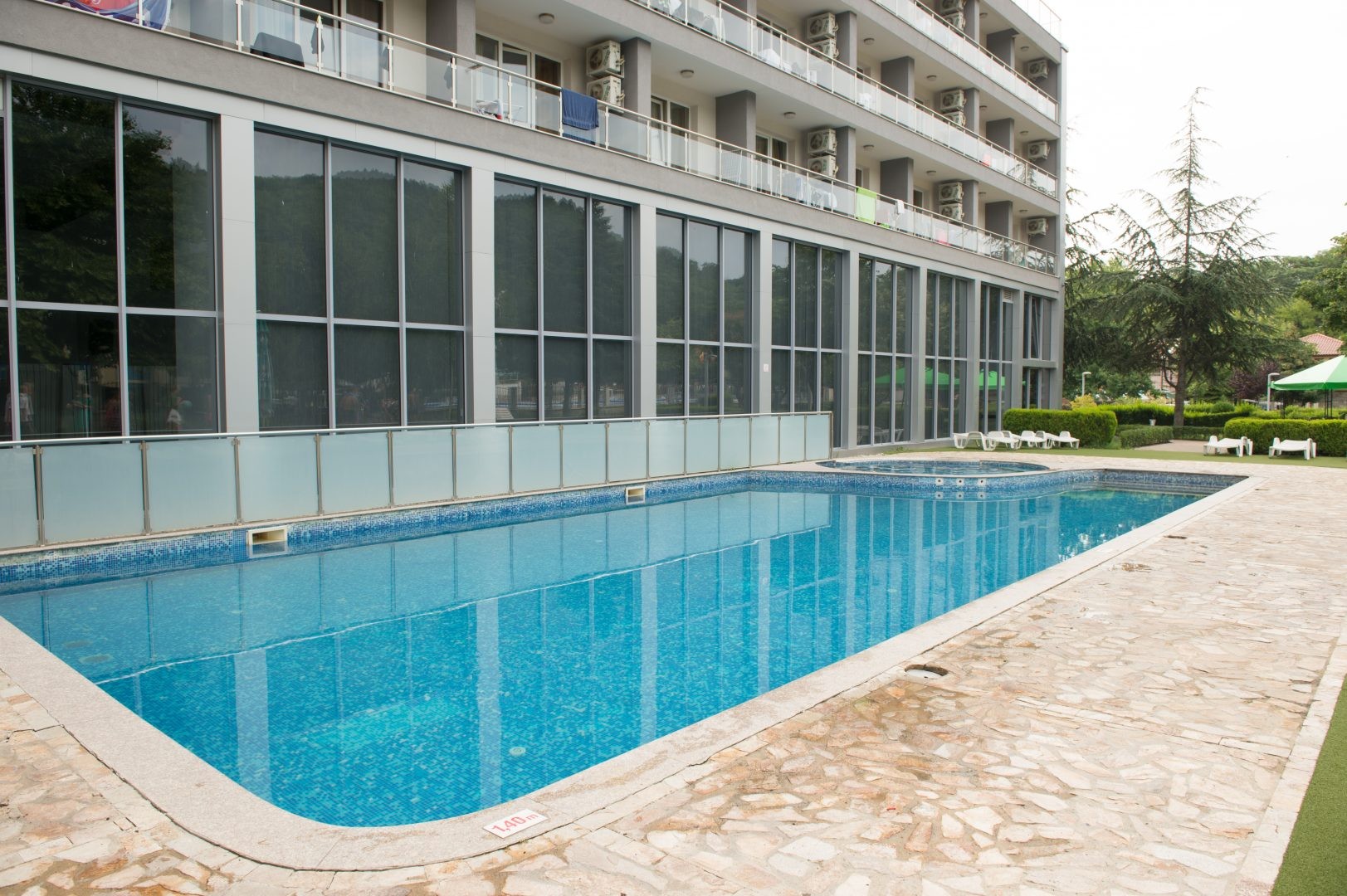 Piscine extérieure rectangulaire à côté de la façade de l'hôtel et de la terrasse, adaptée pour la récupération après les entraînements