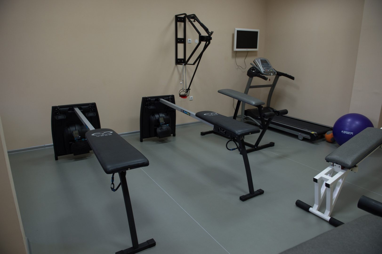 Petite salle d'entraînement avec bancs, tapis de course, espaliers et ballons d'exercice pour les entraînements des athlètes
