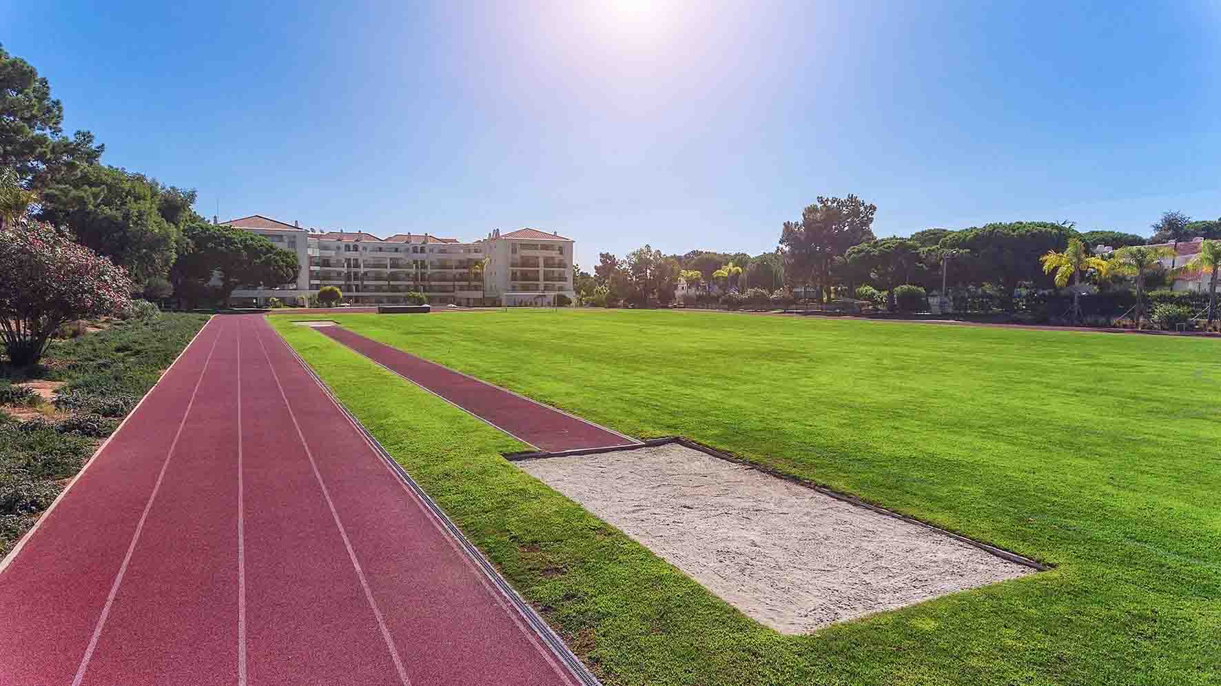Athletics track with long-jump sand pit beside a grass infield.