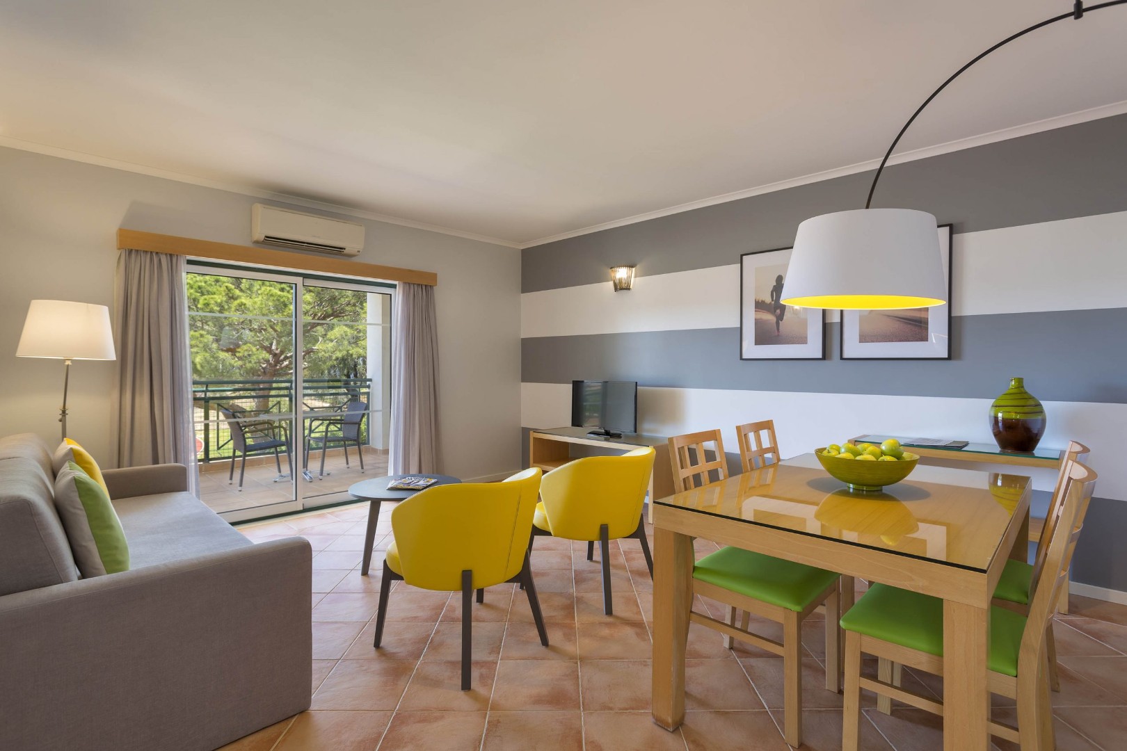 Apartment living and dining space with sofa, table, and balcony seating.