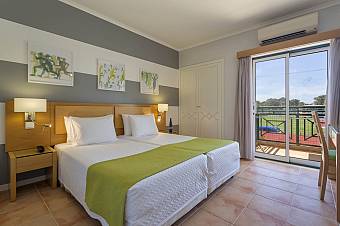 Twin-bed guest room with balcony and view toward the sports field.