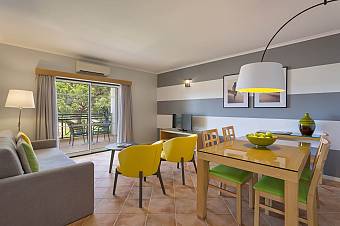 Apartment living and dining space with sofa, table, and balcony seating.