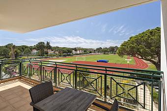 Balcony with table overlooking an athletics track and grass field.