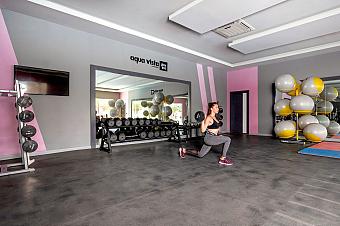 Athlete performing dumbbell lunge in gym with fitness balls and mats