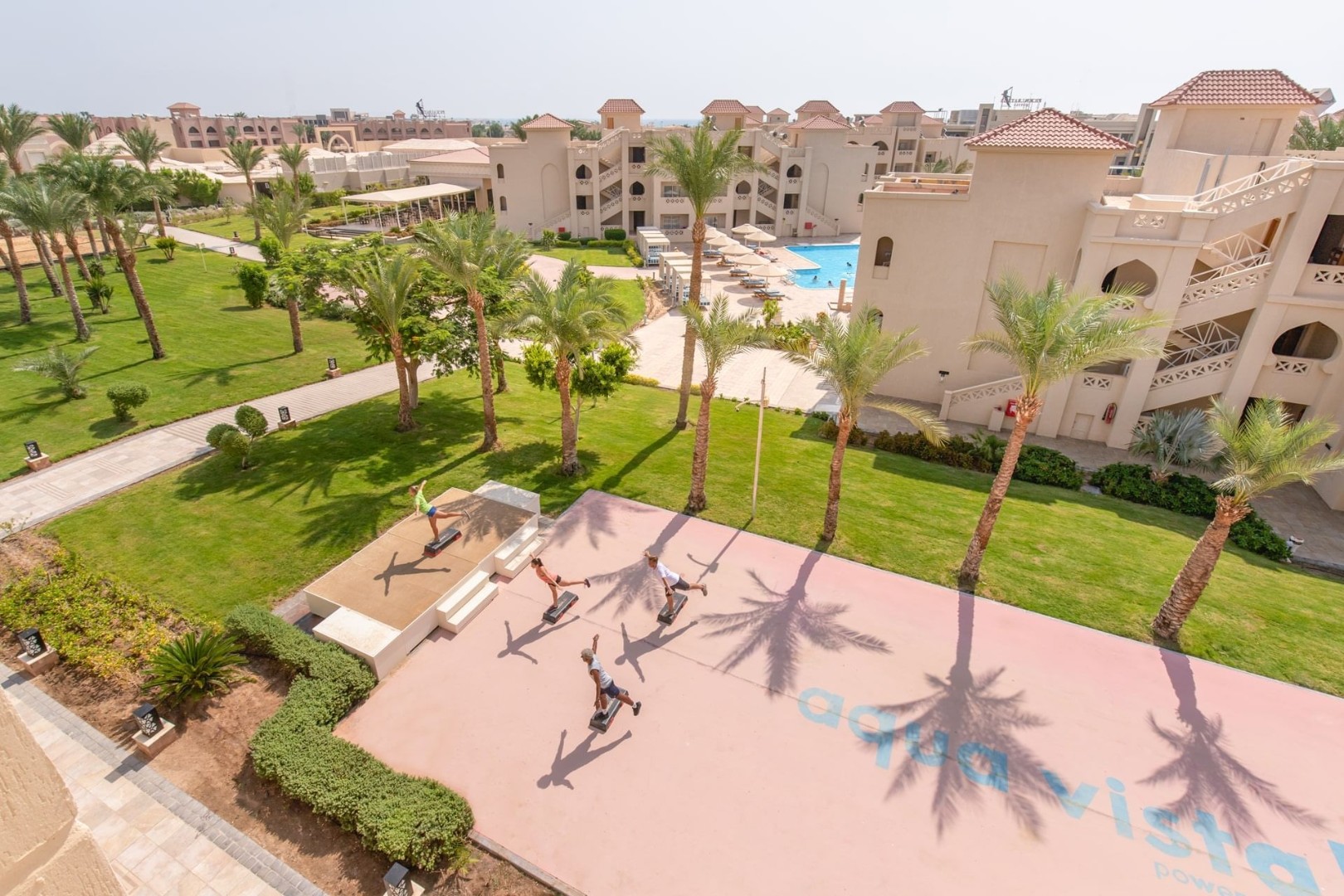 Aerial view of resort gardens with athletes training on outdoor court