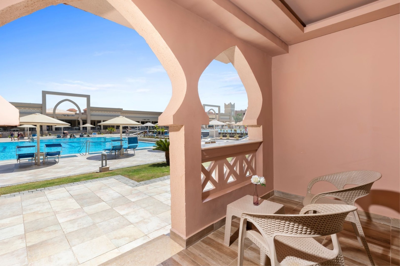 Resort terrace with chairs overlooking swimming pool and umbrellas