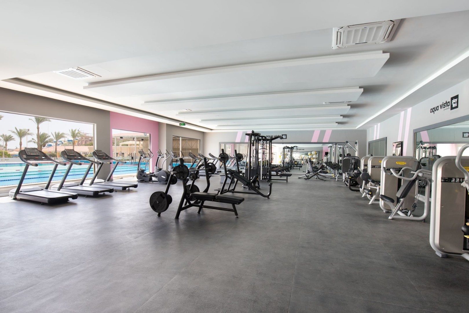 Spacious gym with treadmills, weight machines, and poolside view