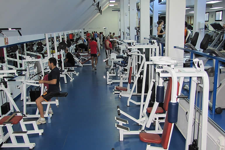 Salle de musculation avec appareils de résistance et postes de renforcement musculaire.