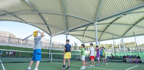 Court de tennis couvert avec joueurs en séance d'entraînement collectif.