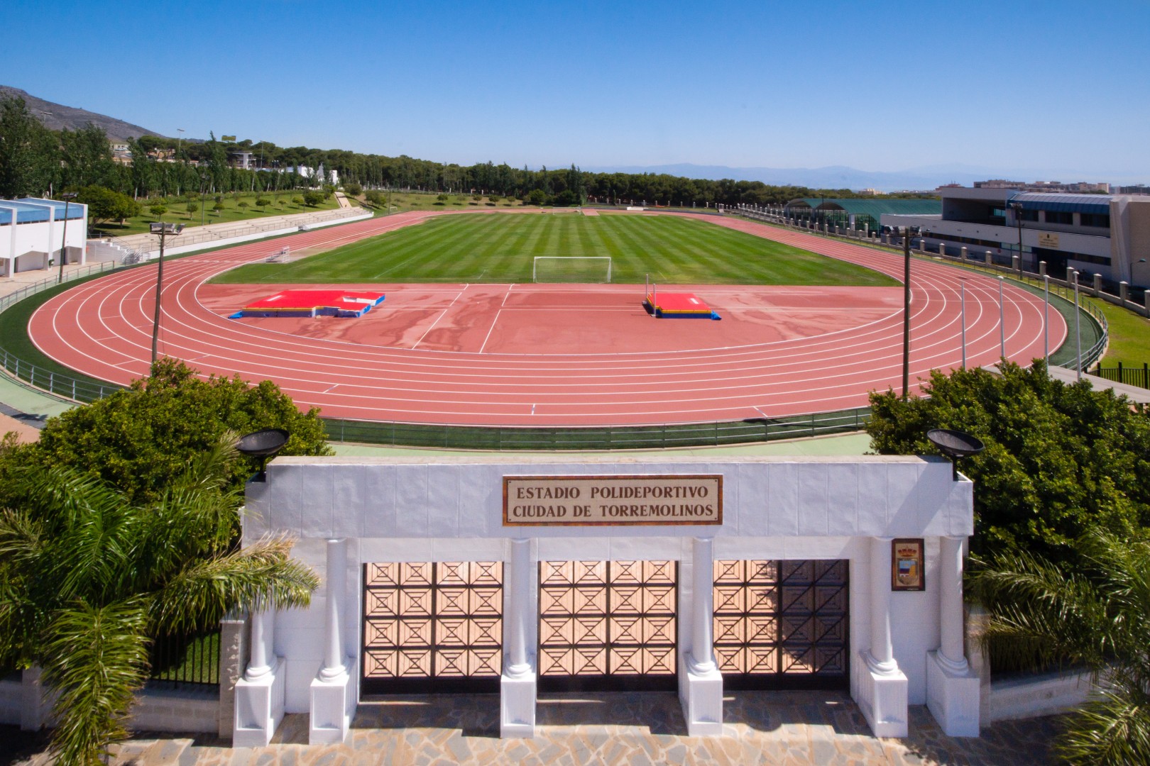 Entrée d'un stade d'athlétisme avec piste de course visible au-delà.