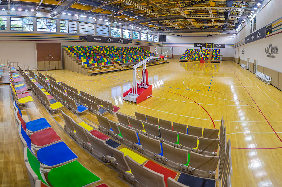 Indoor arena with a polished hardwood court and tiered spectator seating, ideal for matches and tournament play. Professional lighting and clear court markings ensure excellent training conditions.
