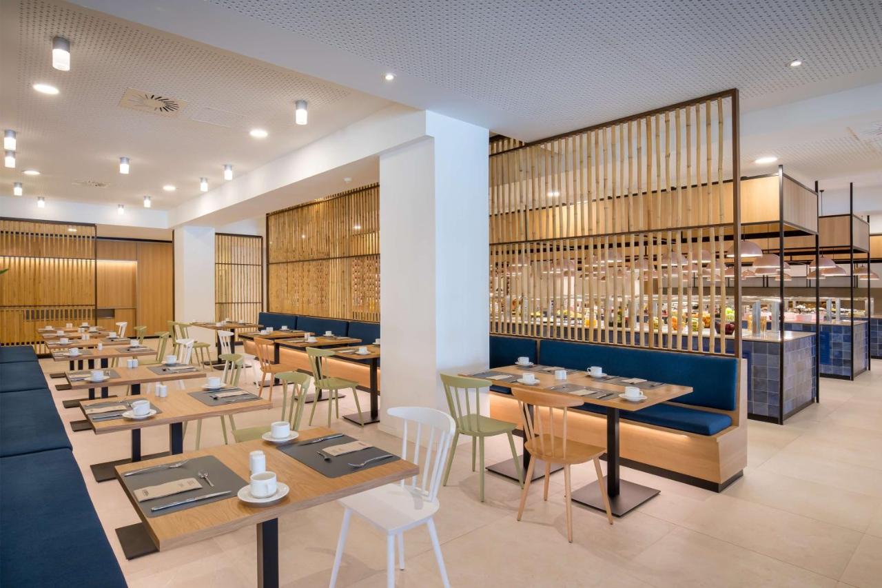 Helles Buffetrestaurant mit Holztrennwänden, Sitzbänken und Esstischen.