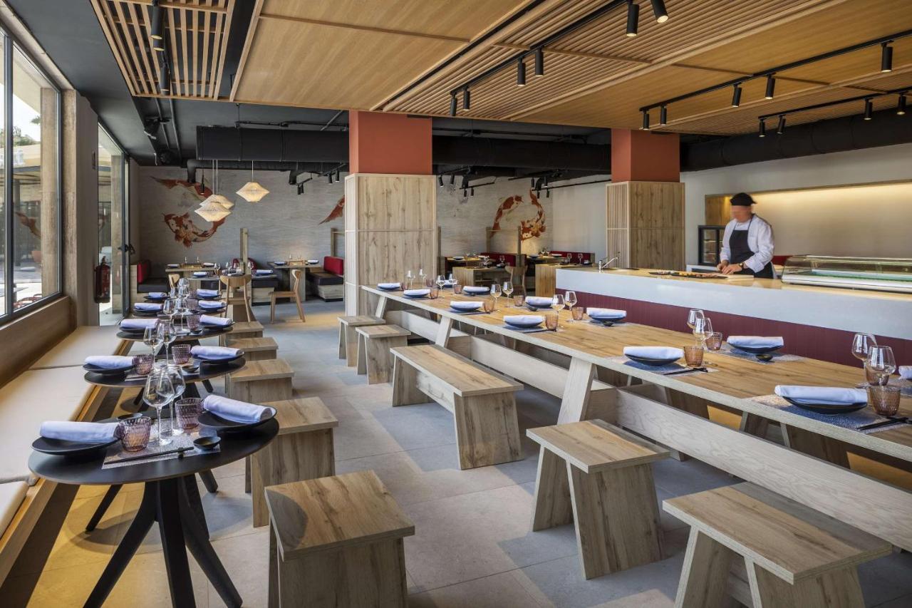 Restaurantinnenraum mit gedeckten Tischen, Bankplätzen und offener Küchentheke.