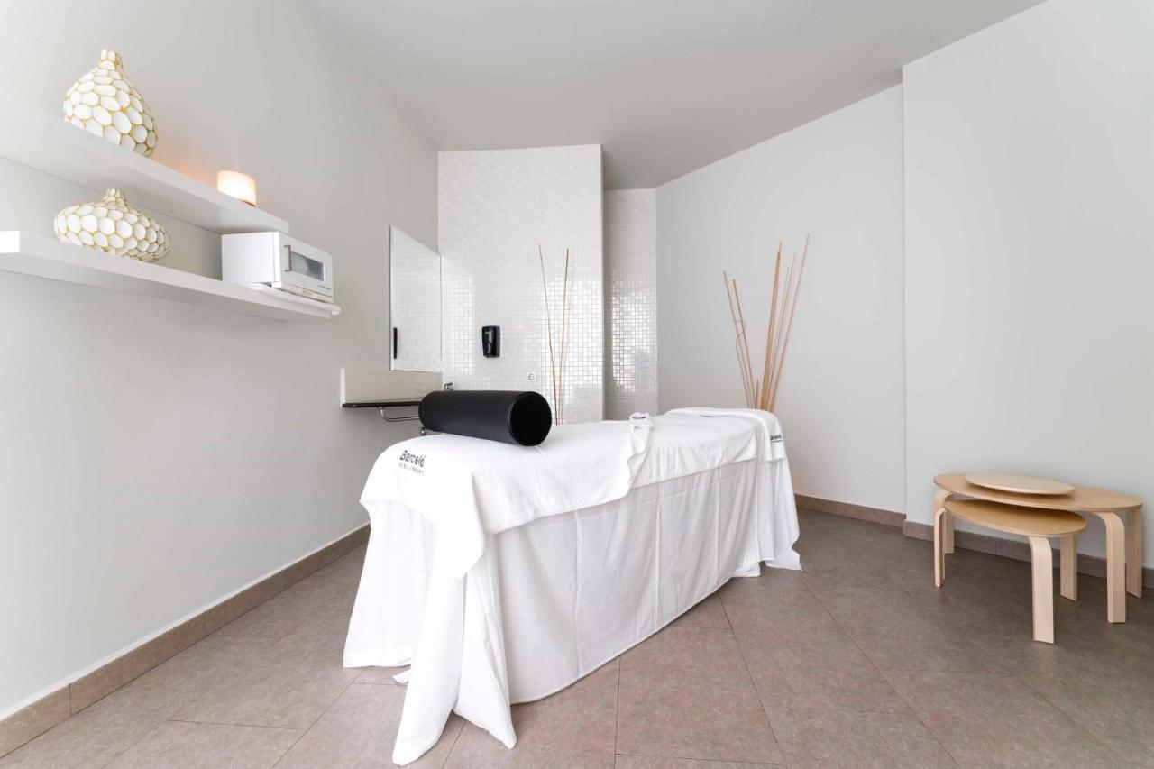 Schlichter Spa-Behandlungsraum mit Massageliege und neutralem Dekor.