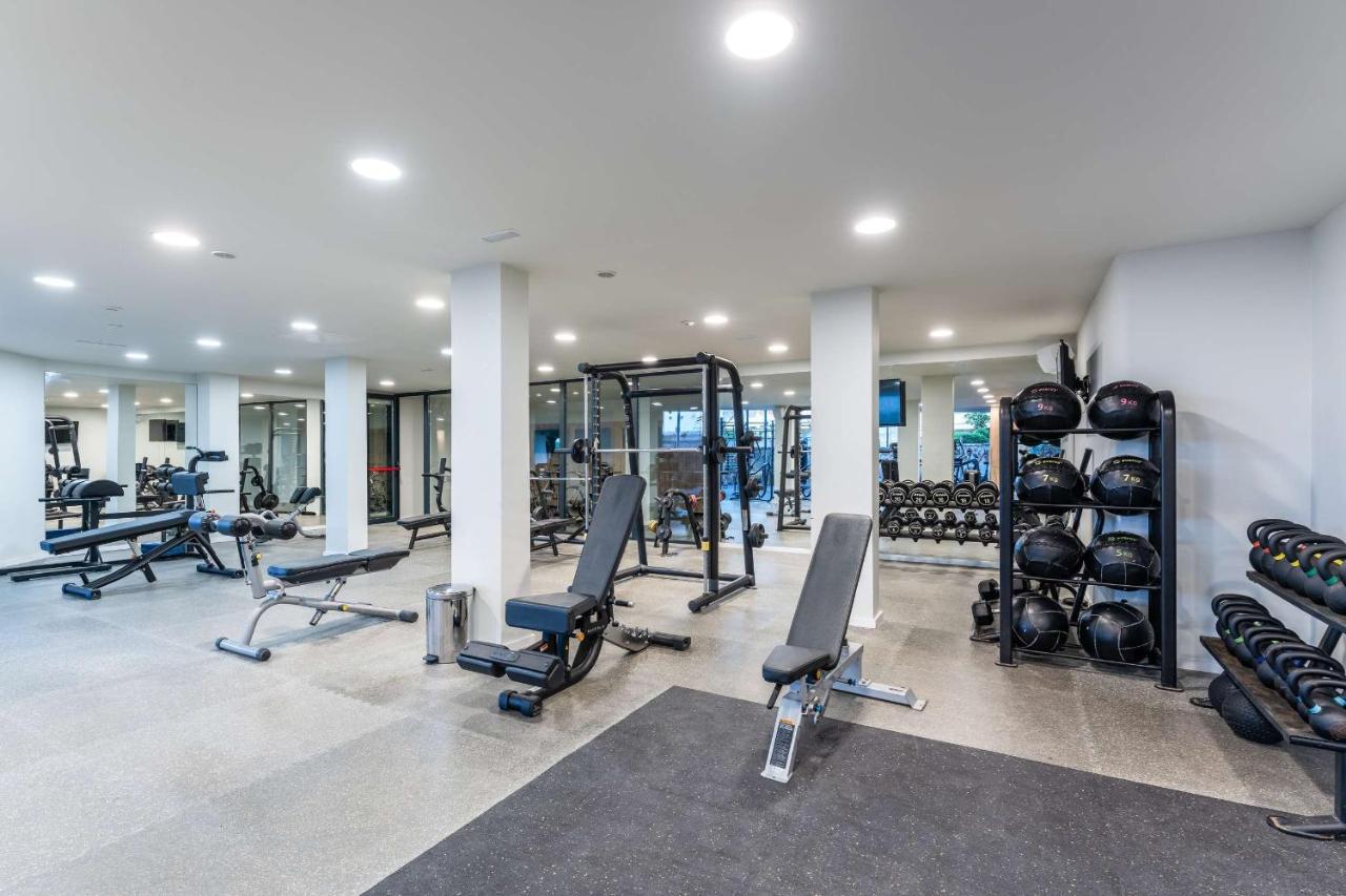 Fitnessraum mit Kraftgeräten, freien Gewichten und Spiegelwänden.