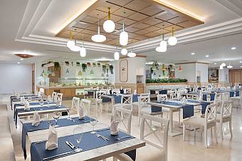 Bright restaurant dining hall with buffet counters and set tables.