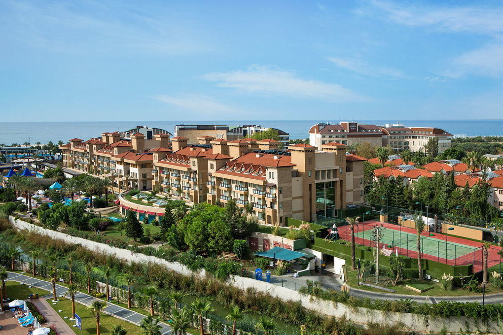 Panoramic view of the resort buildings with landscaped grounds and tennis courts.