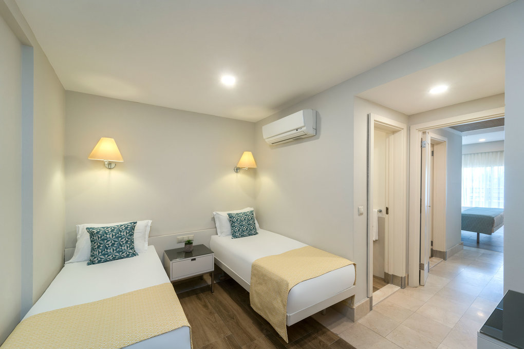 Suite with two single beds and a hallway to a separate bedroom.