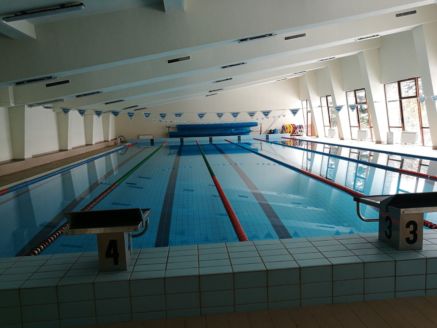 Piscine de natation intérieure avec lignes de couloirs et plots de départ, utilisée pour les entraînements de natation en stage