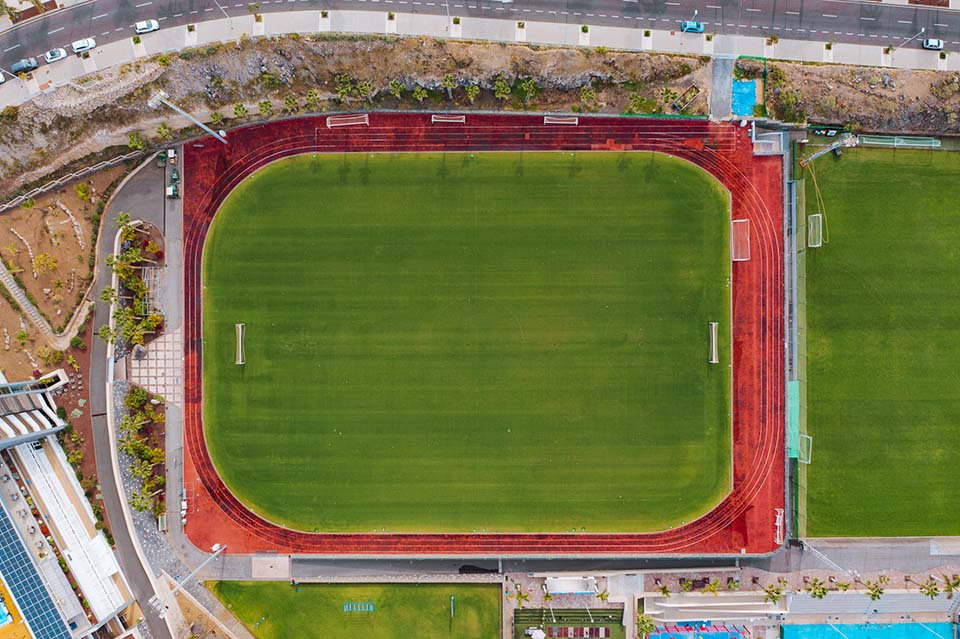 Aerial view of athletics track surrounding a natural grass field.