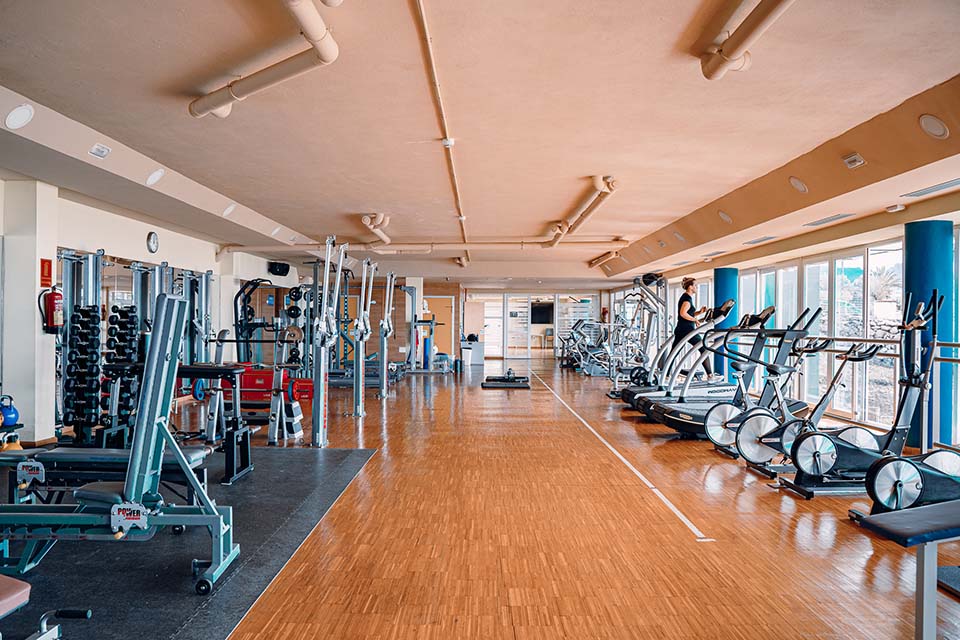 Gym with treadmills, bikes and strength stations along floor-to-ceiling windows.